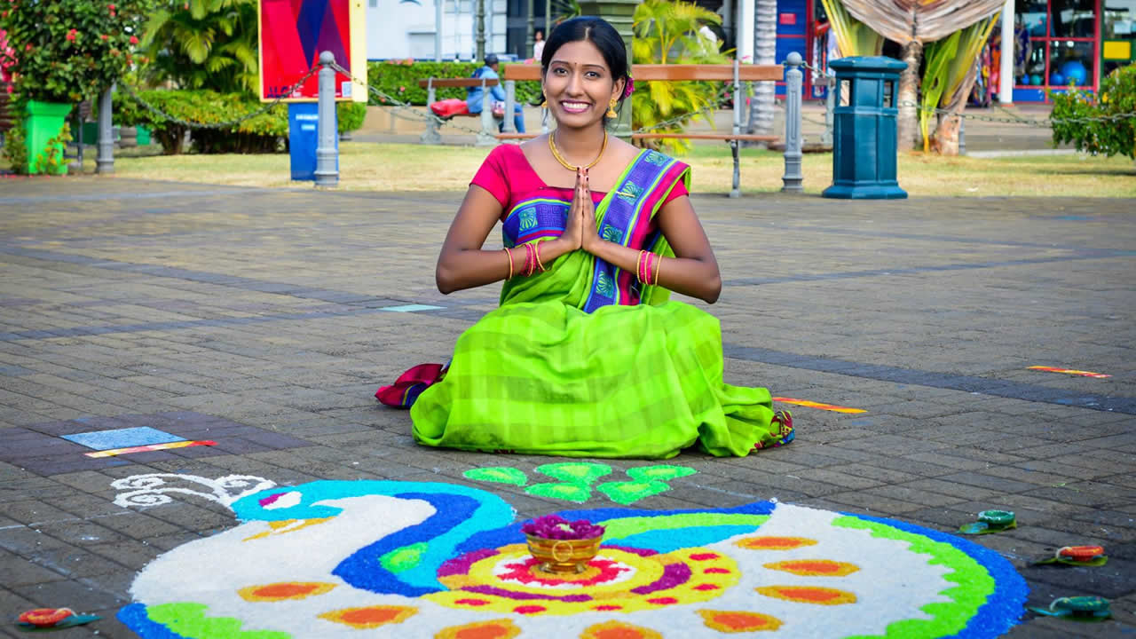Une jeune femme devant un rangoli.