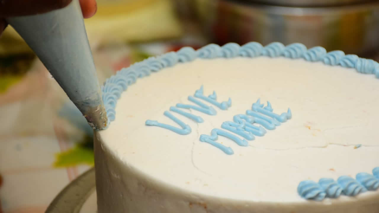 « Vive Marie » s’écrit à l’encre bleue de la crème. L’ensemble est quasi-prêt pour embellir la vitrine de la pâtisserie. 