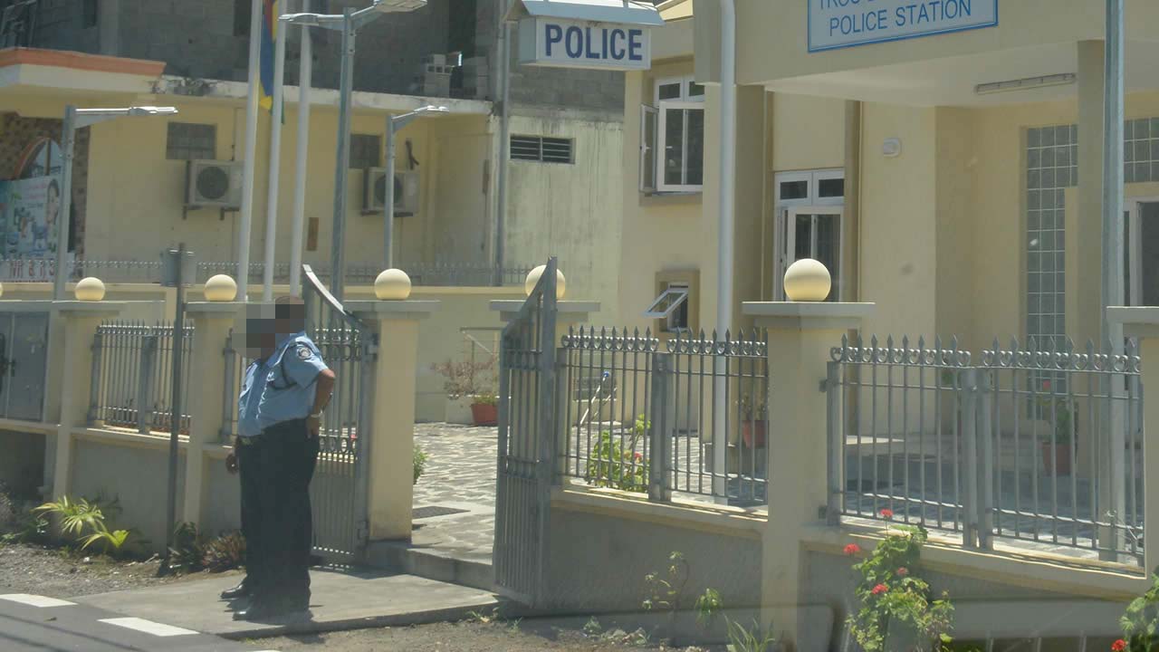 Un des policier en service ne portant pas son couvre-chef devant un poste de police de surcroît.