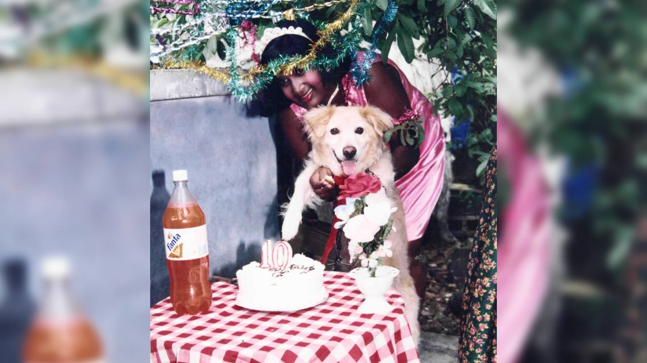 Radha tient son chien pour l’aider à couper son gâteau d’anniversaire. 