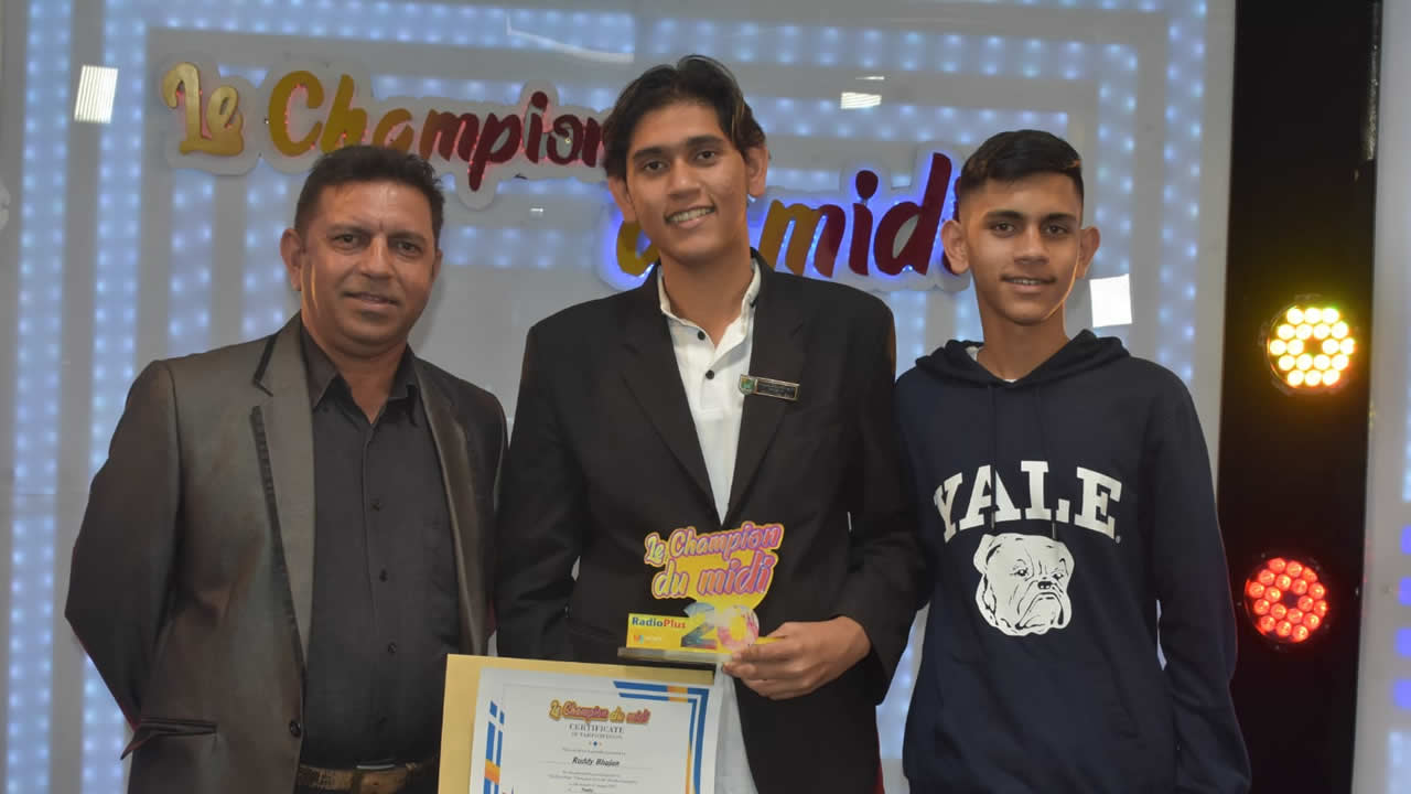 Ruddy Bhujun brandissant fièrement son trophée aux côtés de son père et de son frère. 