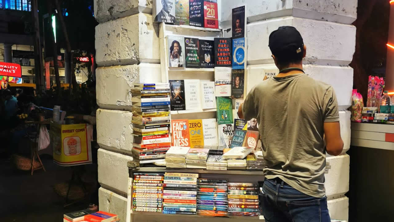 À New Delhi, « the place to be » n’est autre que le Connaught Place où les marchands ambulants côtoient les magasins de marque. Ici, on peut voir un « bookwalah » vendre des livres sur le trottoir.
