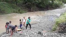 Une femme et six enfants pêchent à Cité La Cure, malgré la montée des eaux