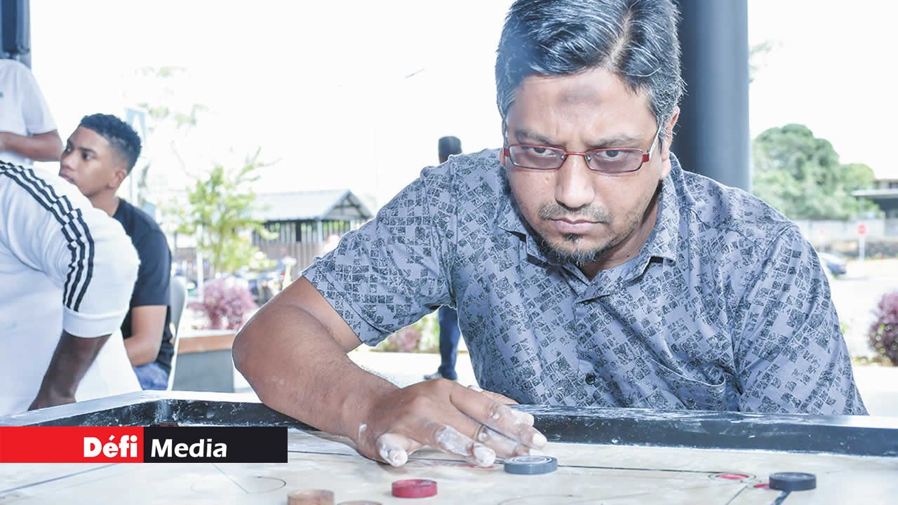 Un joueur concentré réfléchit avec soin avant de lancer son striker.