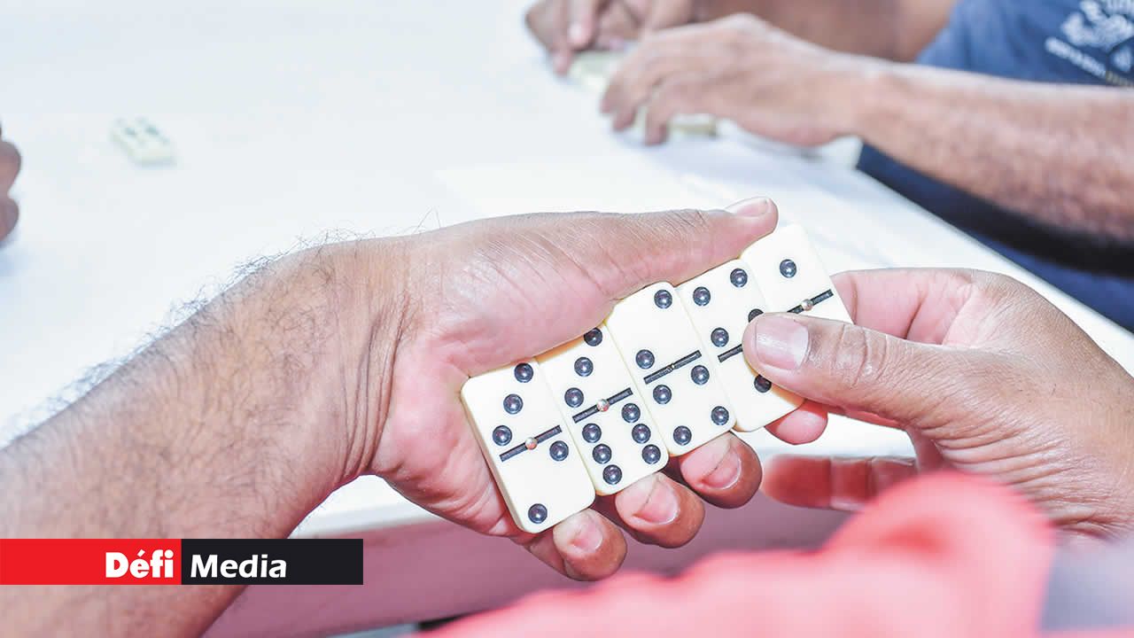 Un participant, dominos en main, patiente sereinement en attendant son tour de jeu.