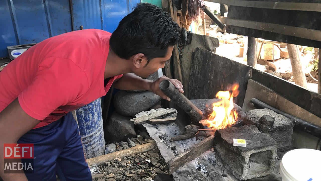 Kevin alimente le feu avec un « poukni ». Dans la mouise à La Ferme