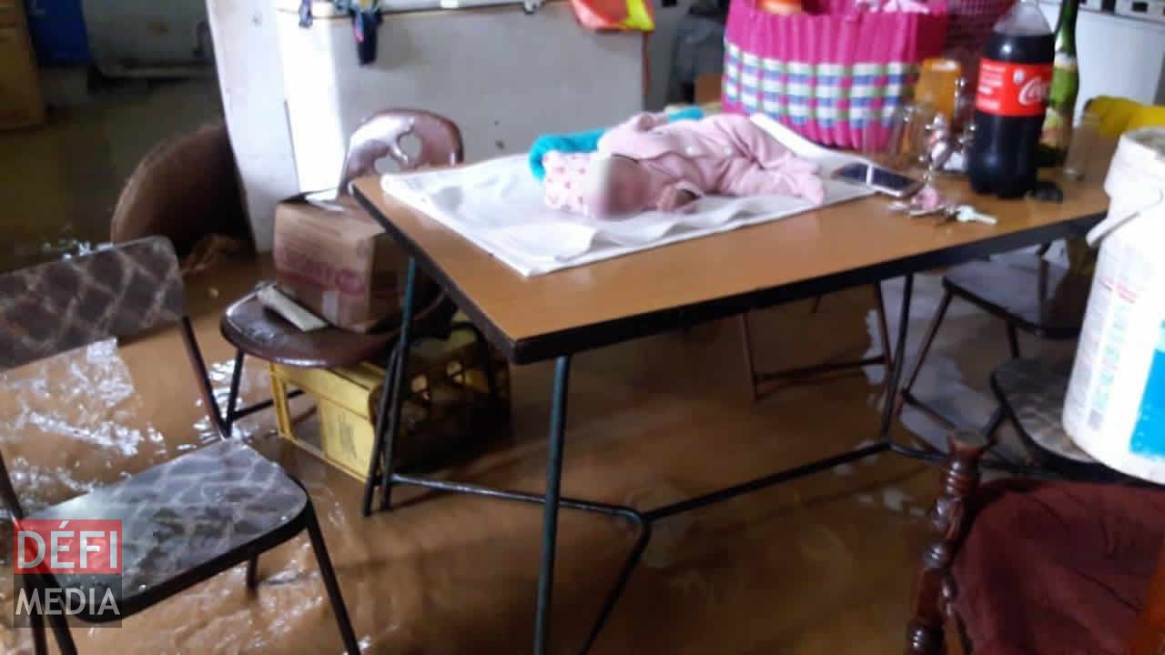 Un bébé dormant paisiblement et posé sur une table à Belle-Source tandis que l’eau a envahi les lieux. Averses