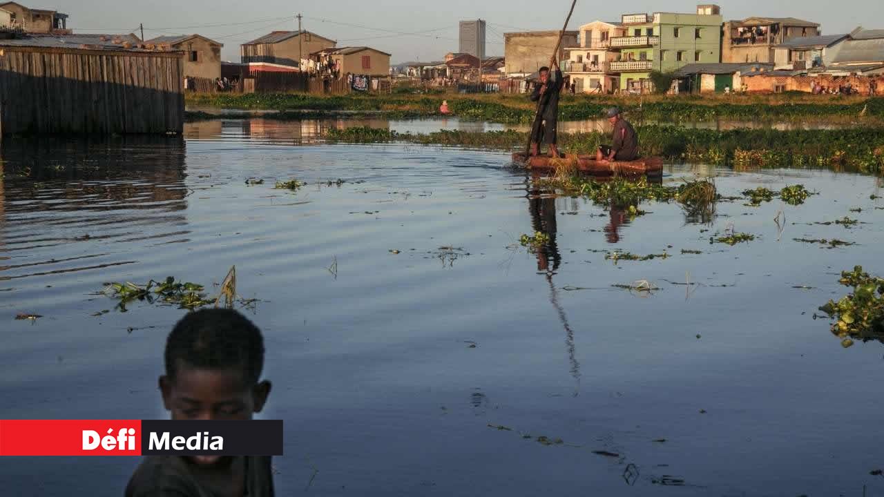 Des habitants du quartier inondé d'Ankasina, utilisant des embarcations de fortune pour rejoindre leurs maisons à Antananarivo, le 28 janvier 2022